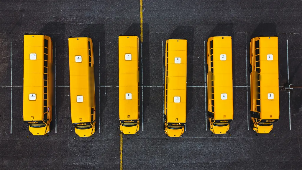 Aerial view of six yellow school buses parked side by side in a lot